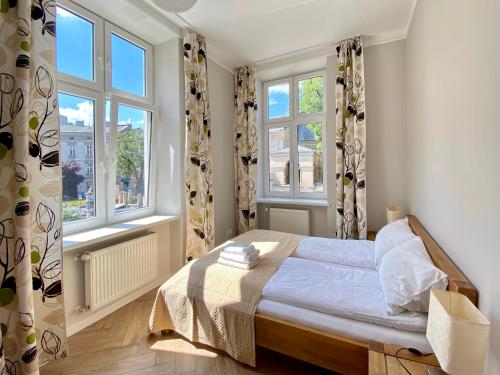 a bedroom with a bed and two windows at Faust Apartments in the Heart of Kazimierz in Krakow