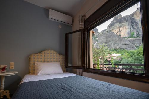 1 dormitorio con cama y ventana grande en The house under the rocks of Meteora 1, en Kalambaka