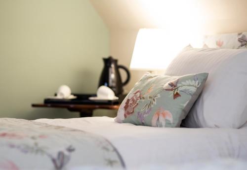 a white bed with a pillow and a table at The Auld Kirk in Ballater