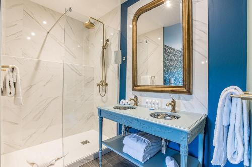 uma casa de banho azul e branca com um lavatório e um chuveiro em Le Relais Des Chartreuses em Le Boulou