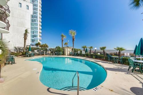 a swimming pool with tables and chairs in a resort at Palms Resort 1502 in Myrtle Beach