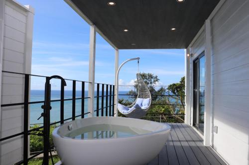 una vasca da bagno sul balcone di una casa di GLORY ISLAND OKINAWA Yabusachi Resort a Nanjo