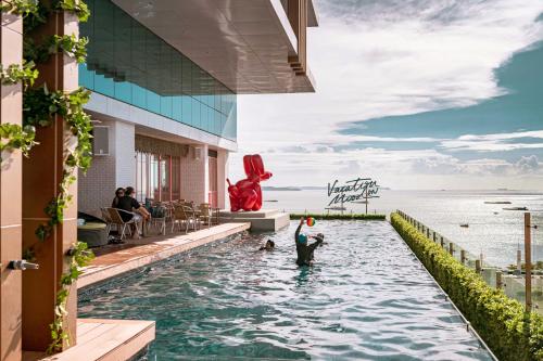 a pool at a resort with two people playing frisbee at Mytt Hotel Pattaya - SHA Extra Plus in Pattaya