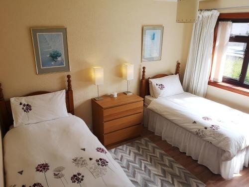 een slaapkamer met 2 bedden en een raam bij Newholme Self-Catering Bungalow in Pitlochry