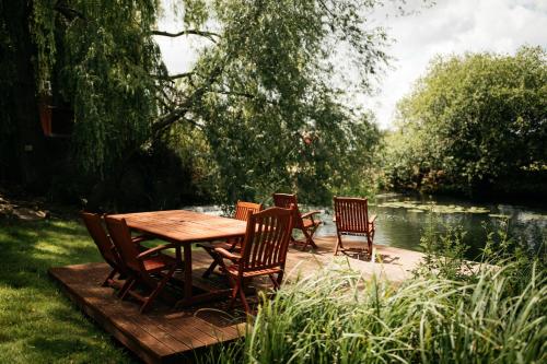 a wooden table and chairs on a deck next to a river at Fletland Mill and Holiday Hamlet - 18th century watermill, in stunning location near Stamford in Stamford