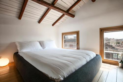 una camera da letto con un grande letto bianco e una finestra di RomeAsYouLike - Babuino Sweet Loft a Roma