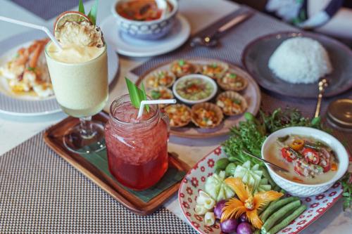 ein Tisch mit Tellern voller Speisen und Getränken in der Unterkunft Mytt Hotel Pattaya in Pattaya