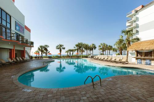 a swimming pool at a resort with chairs and palm trees at Grande Cayman Resort in Myrtle Beach