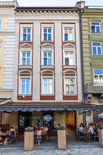 a large building with people sitting at tables in front of it at Oysters & Bubbles Gastro Hotel. Rynok square in Lviv