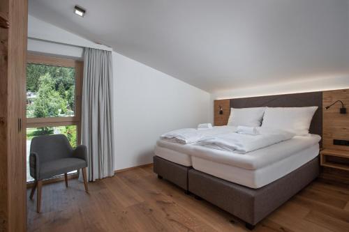 a bedroom with a bed and a chair and a window at See 58 in Zell am See