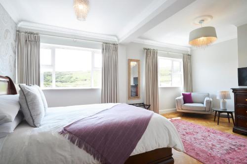 a bedroom with a bed and a chair and windows at Luxury Lodges in Doolin Village with Hot Tubs in Doolin