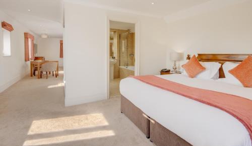a bedroom with a large bed and a bathroom at Nailcote Hall in Berkswell