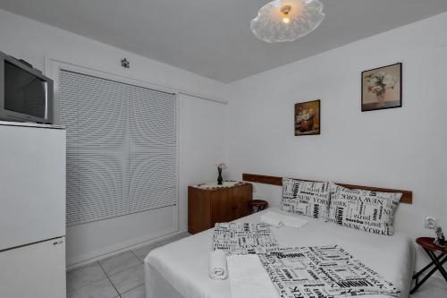 a white room with a bed and a refrigerator and a window at Vila Milena in Krvavica