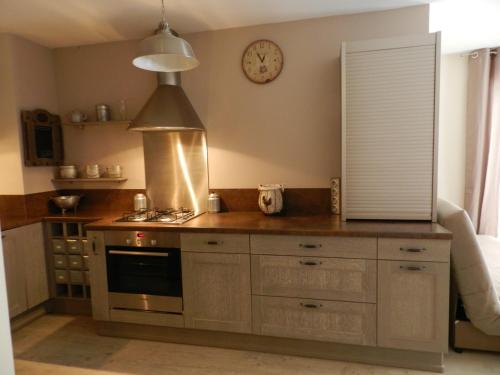 a kitchen with a stove and a clock on the wall at Lac d'Annecy T2 grand jardin in Doussard