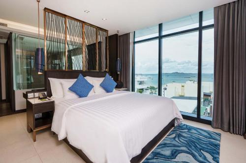 a bedroom with a large bed and a large window at Mytt Hotel Pattaya in Pattaya Central
