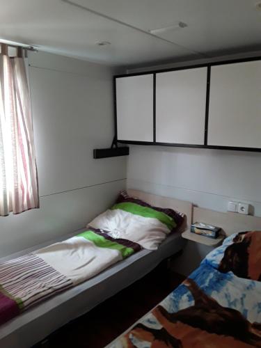 a small bedroom with two beds and a window at Mobilhome Privlaka in Privlaka