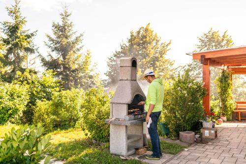 a man standing next to an outdoor oven at Holiday Home Razglednik in Logatec