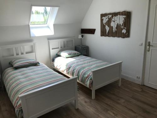 two twin beds in a bedroom with a window at La ferme aux Perdrix in Beuvron-en-Auge