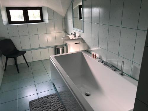 a bathroom with a tub and a sink and a chair at Penzion Hrad in Frýdek-Místek