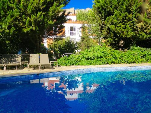 a swimming pool with two chairs and a house at Hotel Kalehan in Selcuk