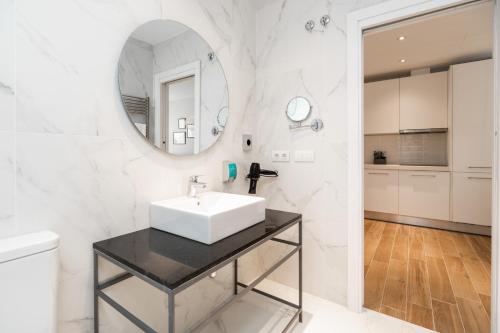 a white bathroom with a sink and a mirror at Tandem Puerto Chico in Cádiz