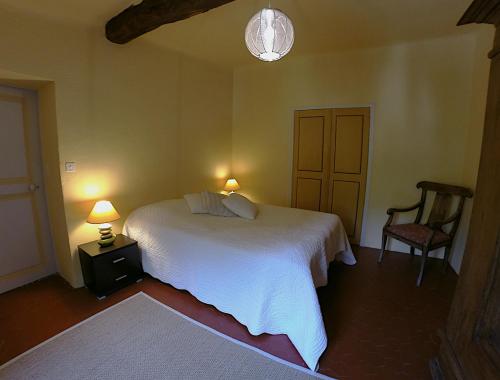 une chambre avec un lit blanc et une chaise dans l'établissement Charmant appartement dans maison de village, à Magagnosc