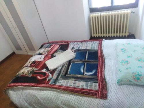 uma cama com uma colcha com uma janela em Appartamento relax em Carenno