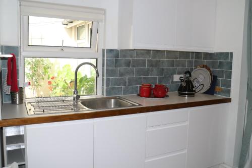 uma cozinha com armários brancos, um lavatório e uma janela em The Holt em Llangollen