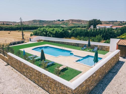 einen Pool in einem Garten mit Sonnenschirmen in der Unterkunft Pátio da Figueira in Torres Vedras
