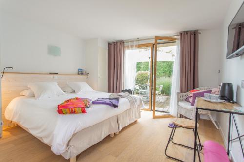 une chambre avec un grand lit blanc et un balcon dans l'établissement LA PETITE PRESQU'ILE, à Locoal-Mendon