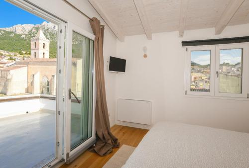 a bedroom with a bed and a large window at Tatta & Nanna Rooms in Oliena