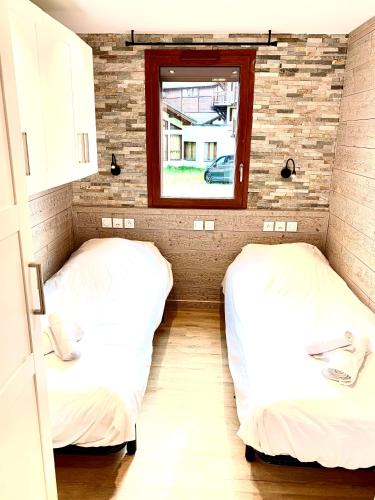 two beds in a small room with a window at Appartement chaleureux au pied des pistes, 4 personnes, wifi in Val Thorens