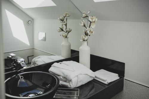 een badkamer met een wastafel en 2 vazen en handdoeken bij viterbo'8 - The Artists House in Porto