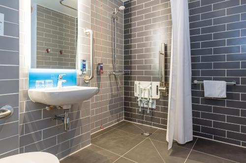 a bathroom with a sink and a shower with blue tiles at Holiday Inn Express - Bodmin - Victoria Junction by IHG in Bodmin