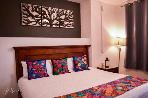 a bedroom with a bed with colorful pillows at Del Centro Hotel Bernal in Bernal