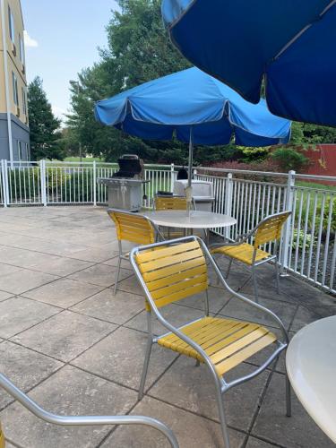 a table and chairs with a blue umbrella at Baymont by Wyndham Chambersburg in Chambersburg