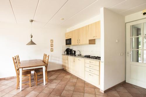 a kitchen with a wooden table and a table and chairs at Vakantiehuisjes Op De Horst in Groesbeek