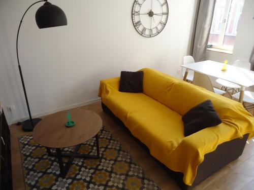 a yellow couch in a living room with a table at Appartement Lille/1ch/stationnement gratuit in Lille