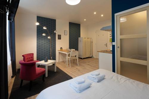 um quarto com uma cama branca e uma cadeira vermelha em Trankil-Apparts Centre 2 em Saint-Quentin