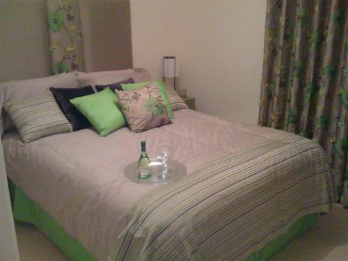 un letto con una bottiglia e un bicchiere sopra di Apple House Guesthouse Heathrow Airport a Hillingdon