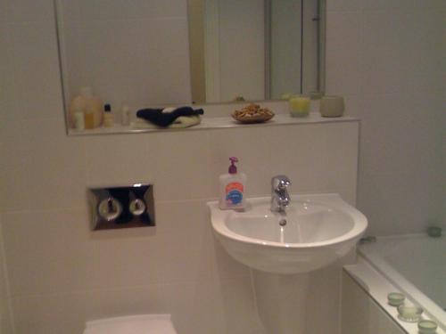 ein weißes Badezimmer mit einem Waschbecken und einem Spiegel in der Unterkunft Apple House Guesthouse Heathrow Airport in Hillingdon