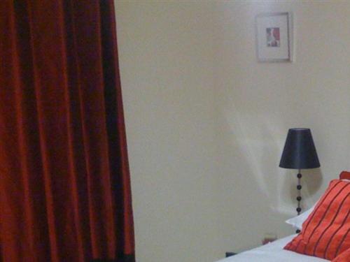 1 dormitorio con cama, lámpara y cortina en Apple House Guesthouse Heathrow Airport, en Hillingdon