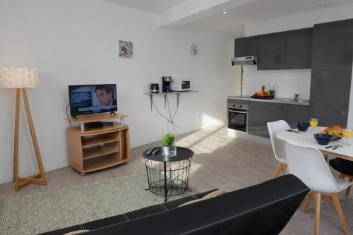 un salon avec un canapé noir et une cuisine dans l'établissement Perle Marine, à Dieppe