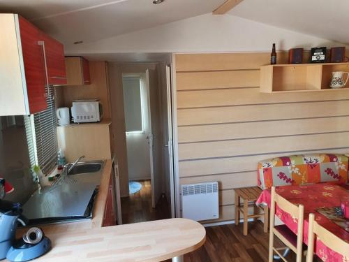 une petite cuisine avec un évier et une table dans l'établissement Mobil Home avec spacieuse terrasse à Meschers proche de Royan, à Meschers-sur-Gironde