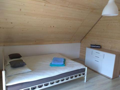 a small bed in a room with a wooden ceiling at Niezapominajka Kopalino in Kopalino