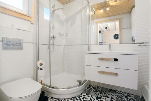 a bathroom with a shower and a toilet and a sink at RODZINKA B&M Całoroczne domki w stylu skandynawskim , podgrzewany basen z mobilnym zadaszeniem in Niechorze