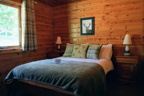 1 dormitorio con 1 cama en una cabaña de madera en Cosy Rowan woodland lodge no1, en Killin
