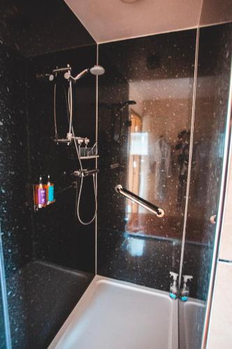 a bathroom with a shower with black tiles at Moorpark Cottages in Barvas