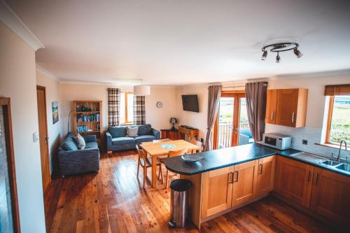 a kitchen and a living room with a table at Moorpark Cottages in Barvas