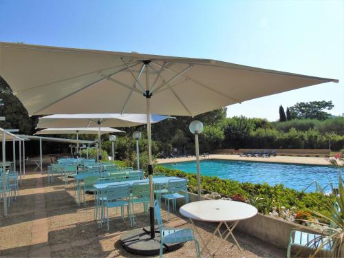 un groupe de tables et de parasols à côté d'une piscine dans l'établissement Domaine Le Moulin Neuf, à Saint-Quentin-la-Poterie